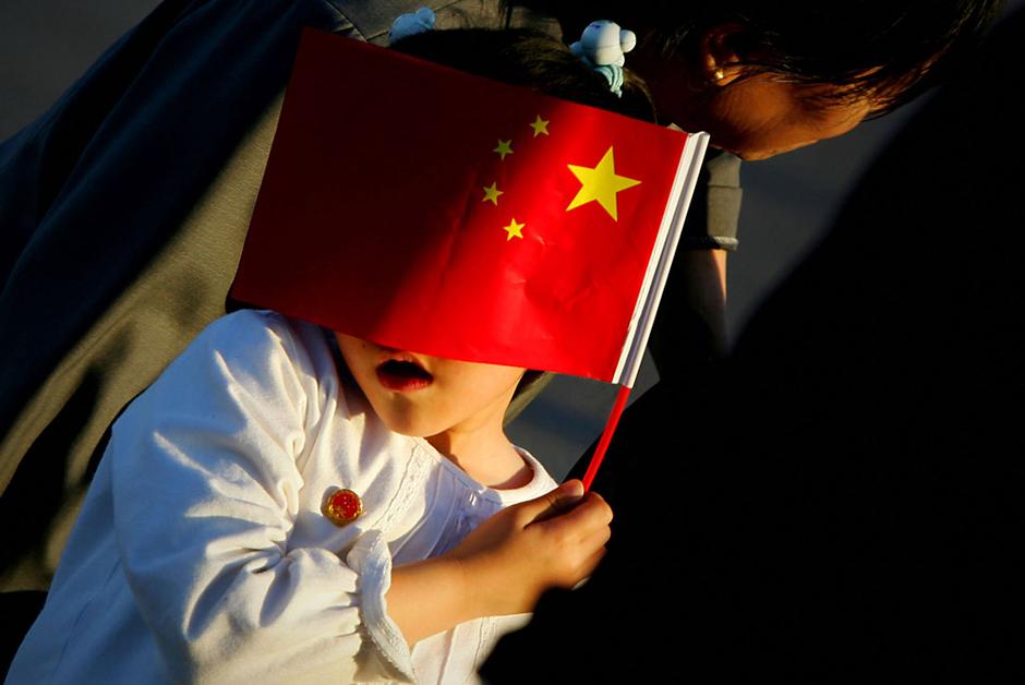 2005年6月2日黄昏,北京天安门广场上,小女孩用手中的国旗遮挡阳光.